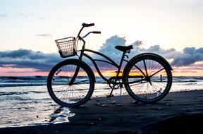 bike is parked on the beach by the sea in the evening