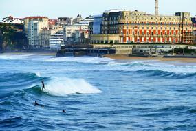 surfers on waves in view of city, france, Biarritz