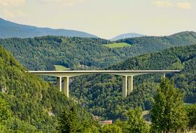 photo of a high pile bridge between green mountains