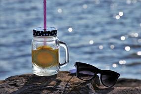 lemonade and sunglasses on a stone against the sea