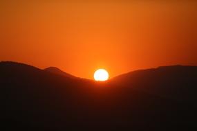 sun over hills at red sky