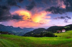 Beautiful landscape of the green mountains with the houses, at colorful gradient sunset, in Italy