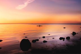 man in a canoe on the baltic sea during sunset