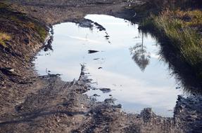photo of a large puddle on a road in the countryside
