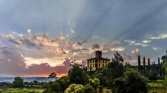 Beautiful landscape of the house, among the green plants, on the mountains, at colorful and beautiful twilight in the clouds