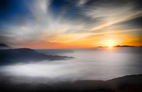 photo of thick fog over the sea at sunset