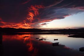 dramatic red clouds above calm water at dusk