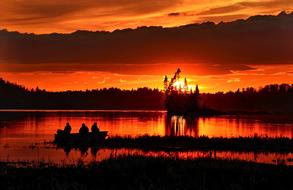fishermen catch fish in a lake in Quebec against the backdrop of a golden sunset