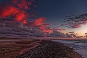 Beautiful landscape of the beach of the North Sea, under red sunset in the clouds, in Denmark
