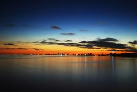 distant view from the water to the illuminated coast at dusk