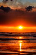 Sun setting in Ocean beneath dark Clouds