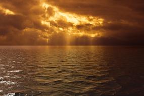 bright rays of the sun make their way through the dark golden clouds
