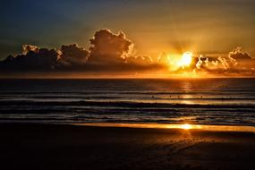Sun mirroring on sea at colorful dusk in the sky