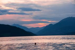 landscape of mountain lake and pink sky at sunset