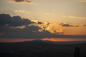 Beautiful colorful sunset in the clouds above the landscape with the hills