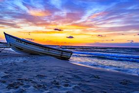 boat on the beach against the backdrop of a colorful sunset