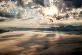 sunbeams bursting through clouds above mountain peaks, Japan, Kumamoto