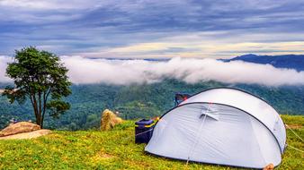 tent on top of a mountain against a cloudy sky