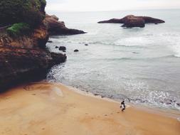 surfer on a sandy beach on the background of rocks