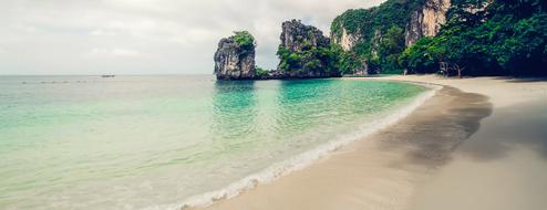 Beautiful and colorful gradient water on the sandy beach with rocks in plants
