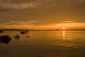 sunset on the horizon is reflected in the water