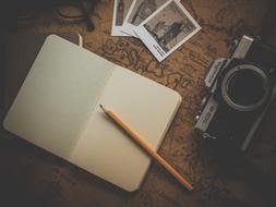 pencil on notepad and vintage camera lie on the table