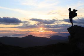 Silhouettes of a person on the cliff, on the beautiful landscape at colorful sunset