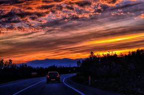 colorful sky over car on road at dusk