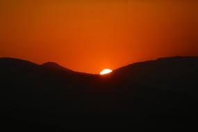 red sunset over black silhouettes of mountains
