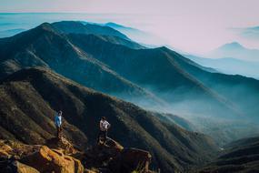 tourists stand on top against the backdrop of foggy mountains