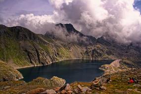 tourists sit on the shore of a mountain lake