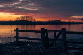 Beautiful landscape with the river behind the fence at beautiful and colorful sunset