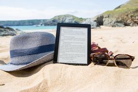 hat, sunglasses and e-book on the beach