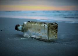 bottle on wet sand at the seaside close up