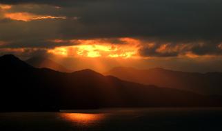 dark clouds and golden sun over a tropical island