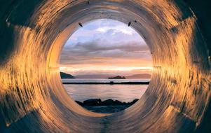 View of coast at dusk through pipe