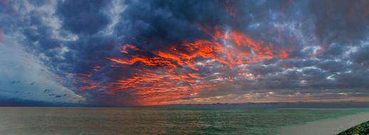 Beautiful and colorful sunset among the clouds above the water