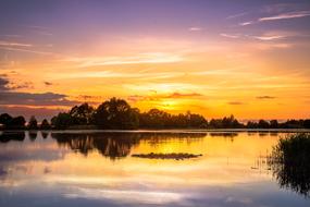 the evening sun reflects on the surface of a calm lake