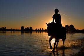 Silhouette of the person on the horse at beautiful and colorful sunset background