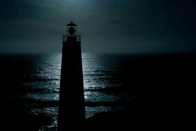 night photo of a lighthouse on the seashore