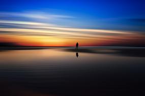 silhouette of a man near the sea at sunset