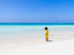 Child on the beautiful sandy beach with beautiful water