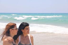 two girls on the beach look at the horizon