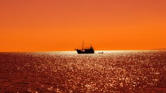Ship boat on the shiny water at beautiful orange and red sunset