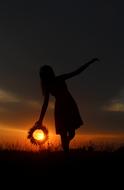 girl with a wreath in hand on the ple on the background of a golden sunset