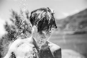 black and white photo of a wet-headed boy on a blurred background