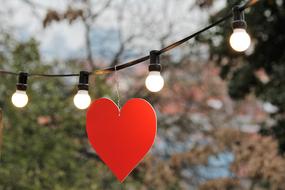 red paper heart hanging on a garland of lamps