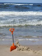 orange toy shovel in the sand on the beach