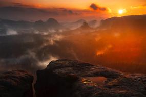 Beautiful mountains in white clouds in red, orange and yellow sunset in Germany