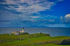 Beautiful landscape of the colorful hills on the coast, with lighthouse and buildings, in Scotland